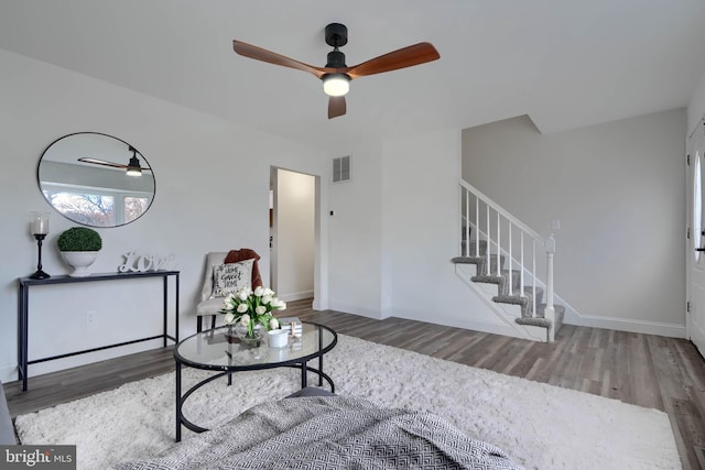 living room with visible vents, stairway, baseboards, and wood finished floors