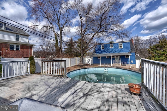 outdoor pool featuring fence and a wooden deck