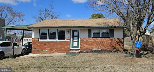 view of front of house featuring an attached carport, fence, brick siding, and roof with shingles