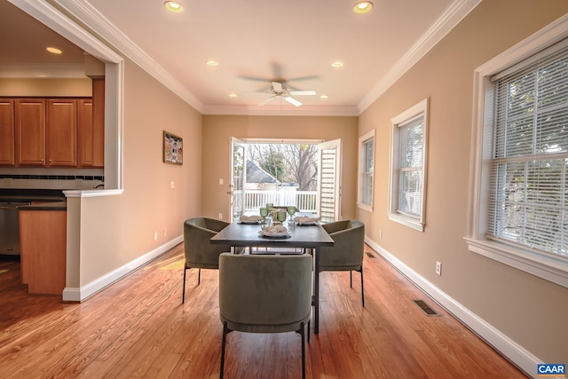 dining space featuring a ceiling fan, baseboards, visible vents, light wood-style flooring, and ornamental molding