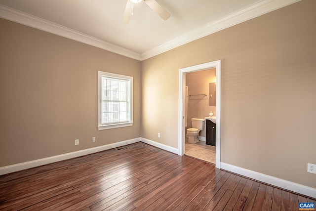 unfurnished bedroom featuring visible vents, baseboards, ornamental molding, ensuite bathroom, and dark wood-style floors