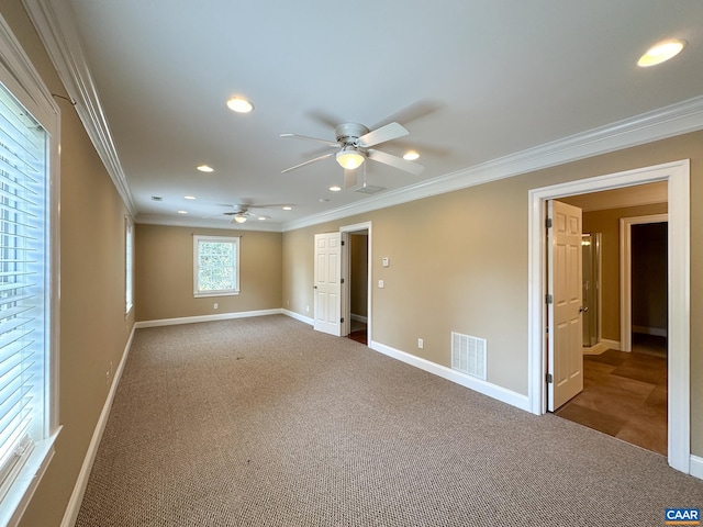 empty room featuring visible vents, carpet, ceiling fan, and ornamental molding