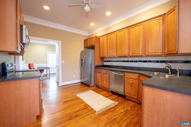 kitchen with dark countertops, tasteful backsplash, ornamental molding, appliances with stainless steel finishes, and a sink