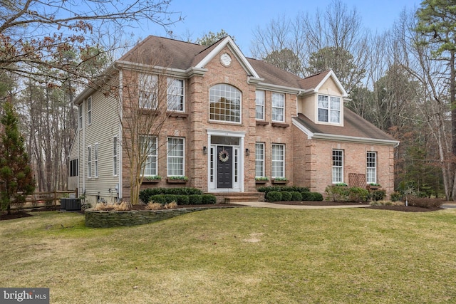 view of front facade with a front lawn, central AC unit, and brick siding