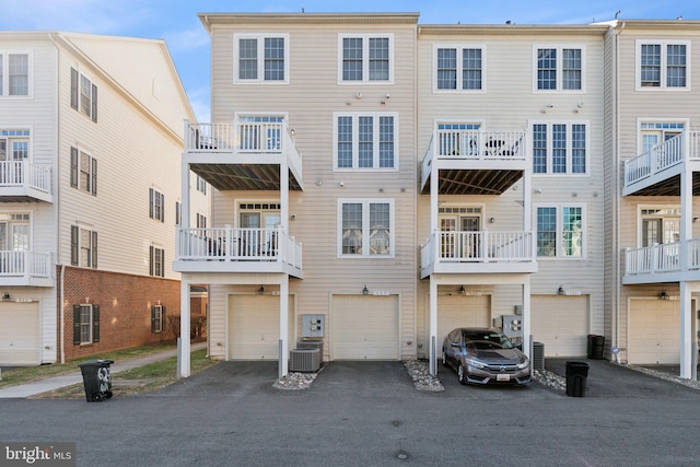 back of property featuring central AC unit, driveway, and an attached garage