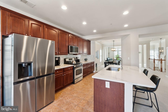 kitchen featuring visible vents, backsplash, a breakfast bar area, appliances with stainless steel finishes, and a sink