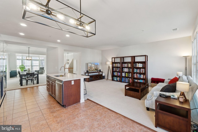 kitchen featuring open floor plan, dishwasher, light carpet, a notable chandelier, and a sink