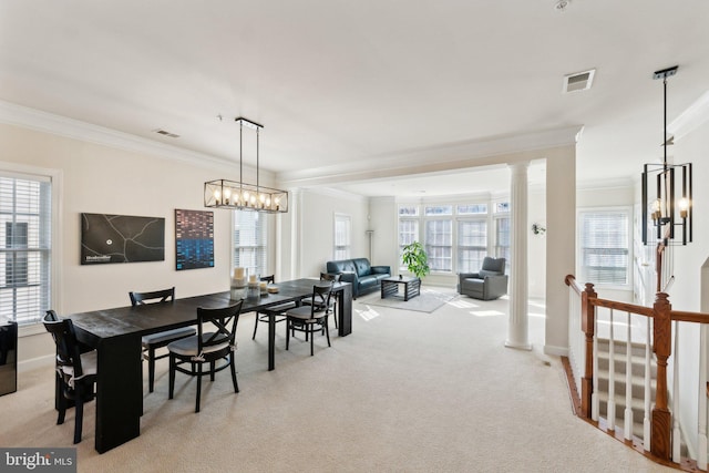 dining space featuring crown molding, a chandelier, ornate columns, and light carpet