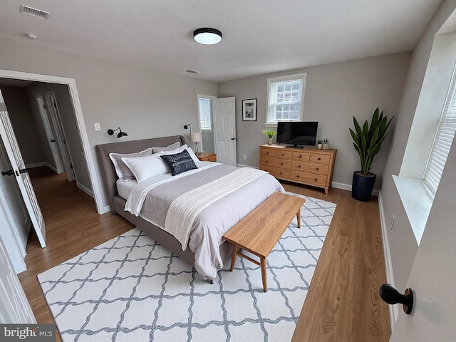 bedroom featuring wood finished floors, visible vents, and baseboards