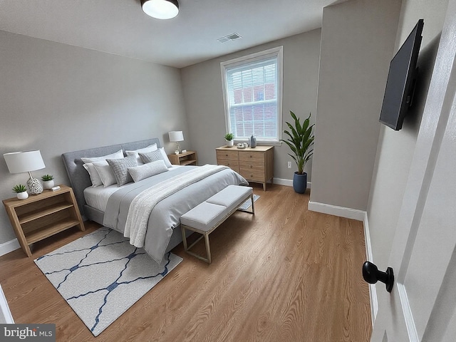 bedroom featuring light wood-type flooring, visible vents, and baseboards