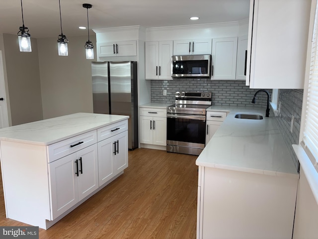 kitchen with light wood-style flooring, a sink, appliances with stainless steel finishes, white cabinetry, and a center island