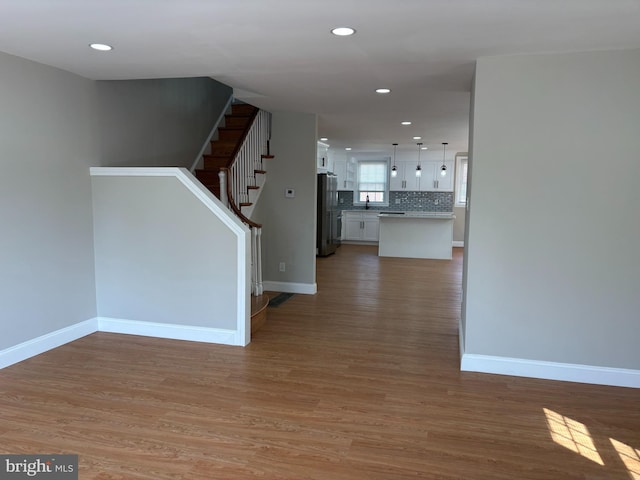 hallway with baseboards, stairs, and light wood-style floors