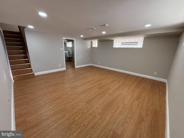 below grade area featuring recessed lighting, baseboards, stairs, and light wood-style floors