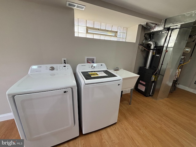 laundry area featuring visible vents, light wood-type flooring, laundry area, heating unit, and independent washer and dryer