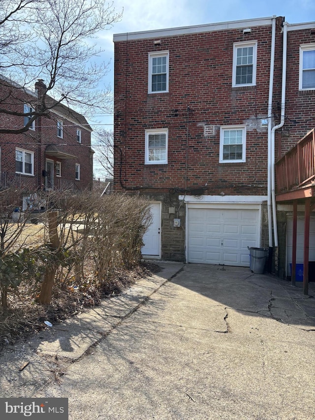 rear view of house with brick siding, concrete driveway, and an attached garage