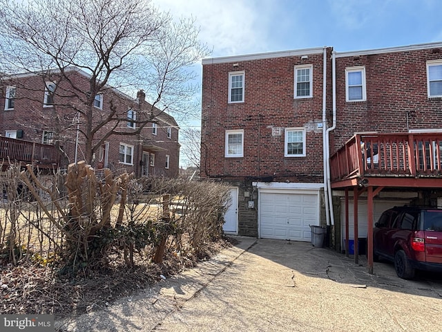 back of house featuring an attached garage, brick siding, and driveway