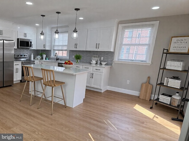 kitchen with tasteful backsplash, white cabinets, stainless steel appliances, and light wood-type flooring