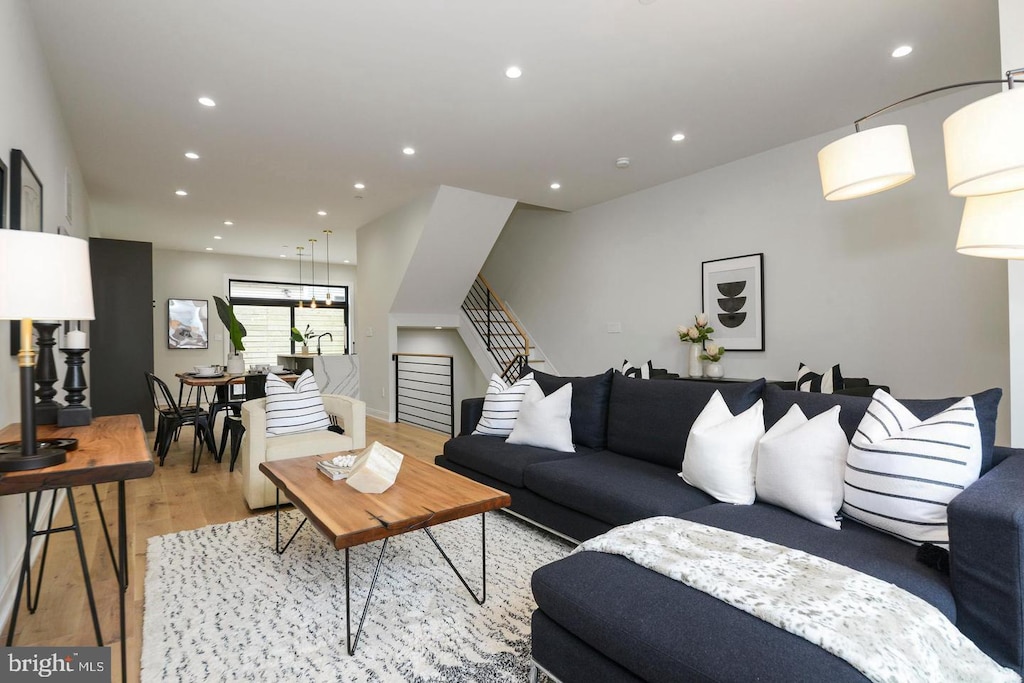 living area with recessed lighting, baseboards, stairs, and light wood-style floors