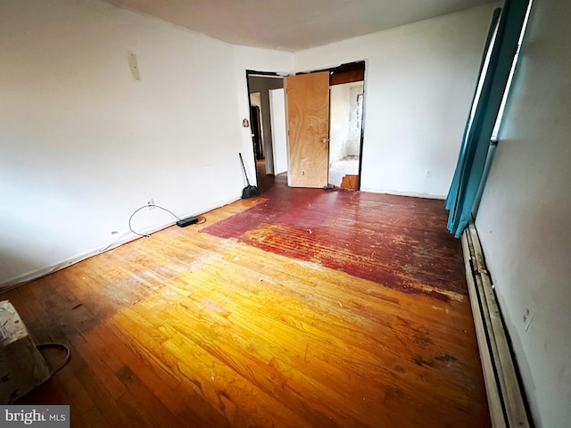 unfurnished room with a baseboard radiator and wood-type flooring