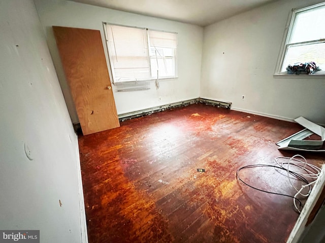 empty room featuring a baseboard heating unit and wood finished floors