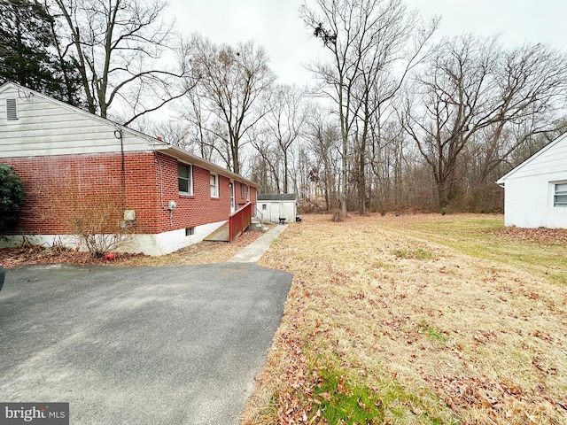 view of home's exterior with brick siding, a lawn, and driveway