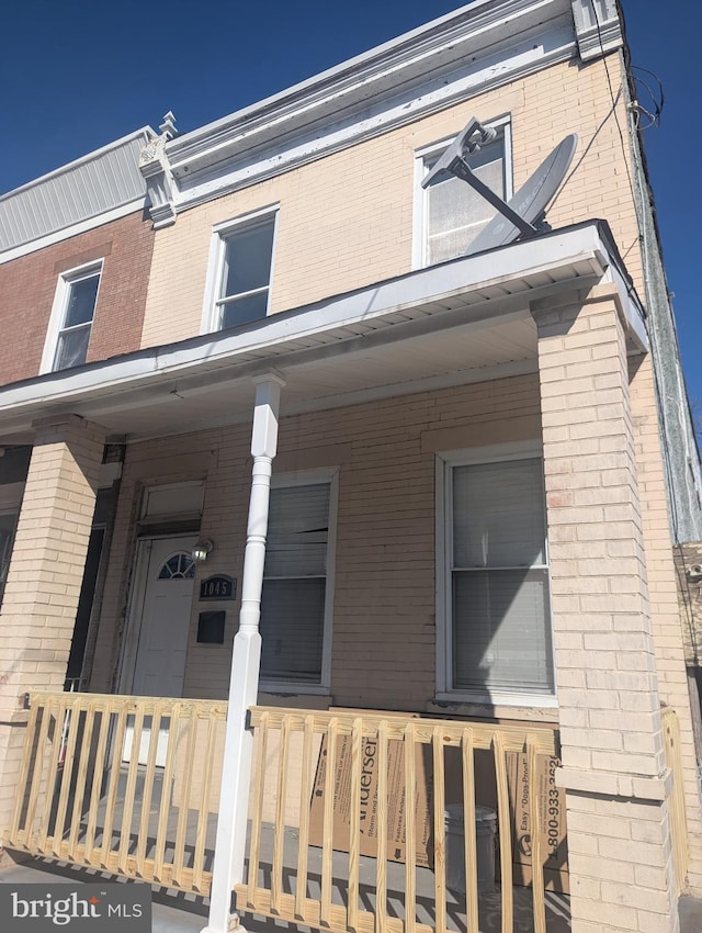 property entrance featuring covered porch and brick siding