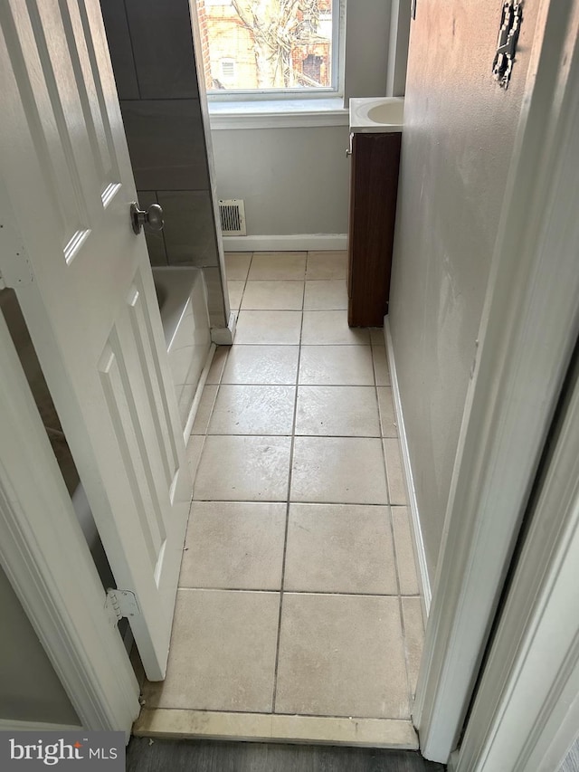 full bathroom with vanity, a bathing tub, baseboards, visible vents, and tile patterned floors