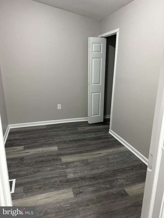 unfurnished room with visible vents, baseboards, and dark wood-style floors