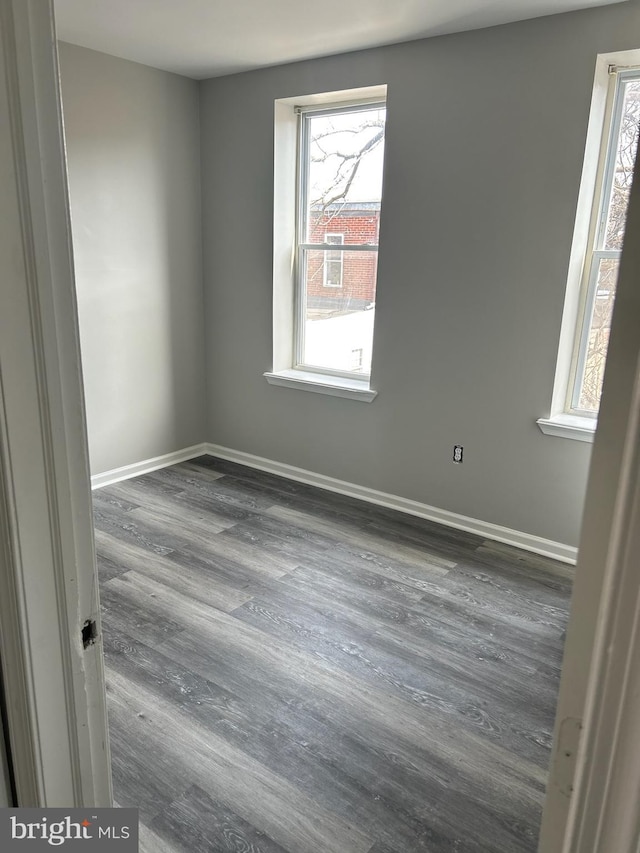 empty room with baseboards and dark wood finished floors