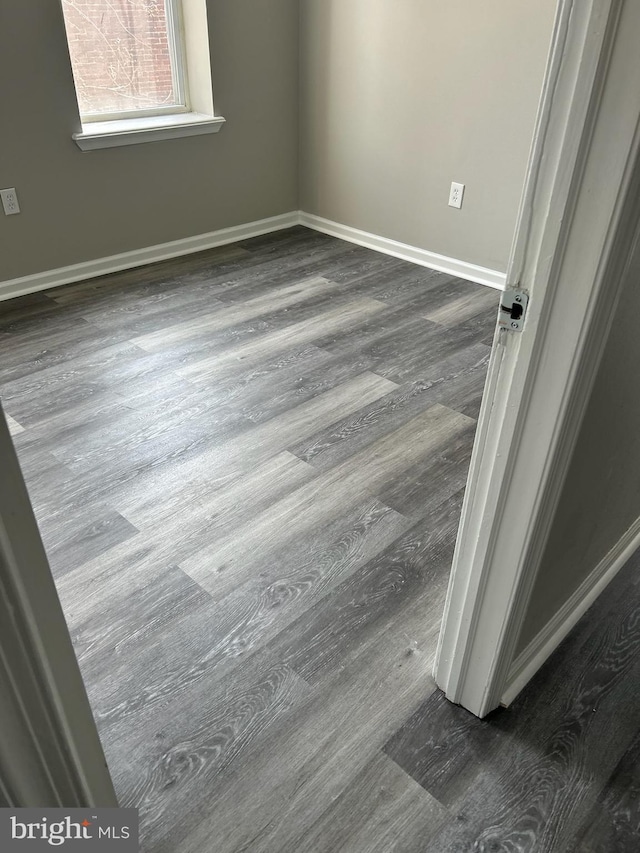 unfurnished room featuring baseboards and dark wood finished floors