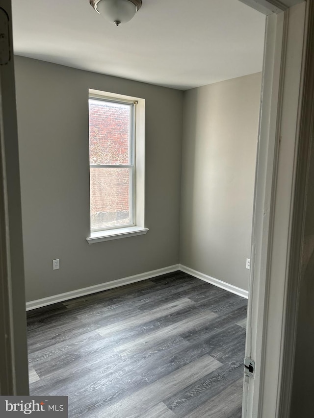 spare room featuring baseboards and wood finished floors