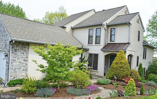 view of front of home featuring stone siding, a shingled roof, a standing seam roof, and metal roof