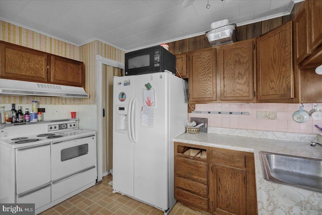 kitchen with under cabinet range hood, a sink, white appliances, wallpapered walls, and light countertops