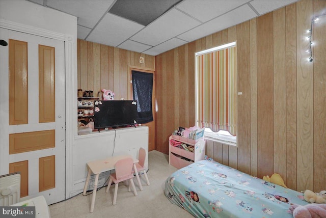 bedroom with a drop ceiling and wood walls