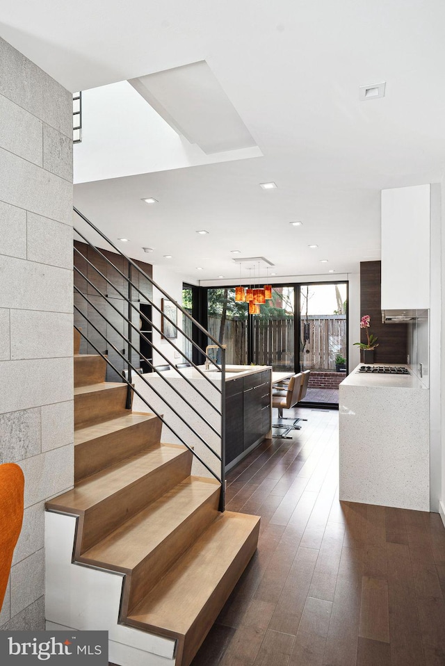 stairway with recessed lighting, wood finished floors, and expansive windows