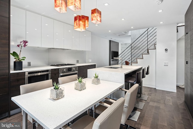 kitchen featuring modern cabinets, an island with sink, a sink, white cabinetry, and stainless steel appliances