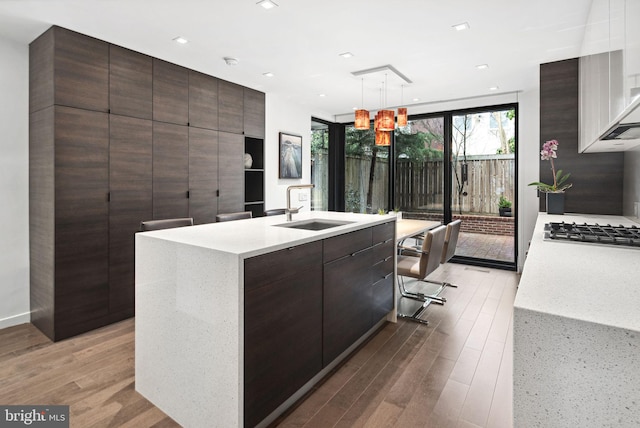 kitchen with light countertops, light wood-style flooring, stainless steel gas cooktop, and a sink