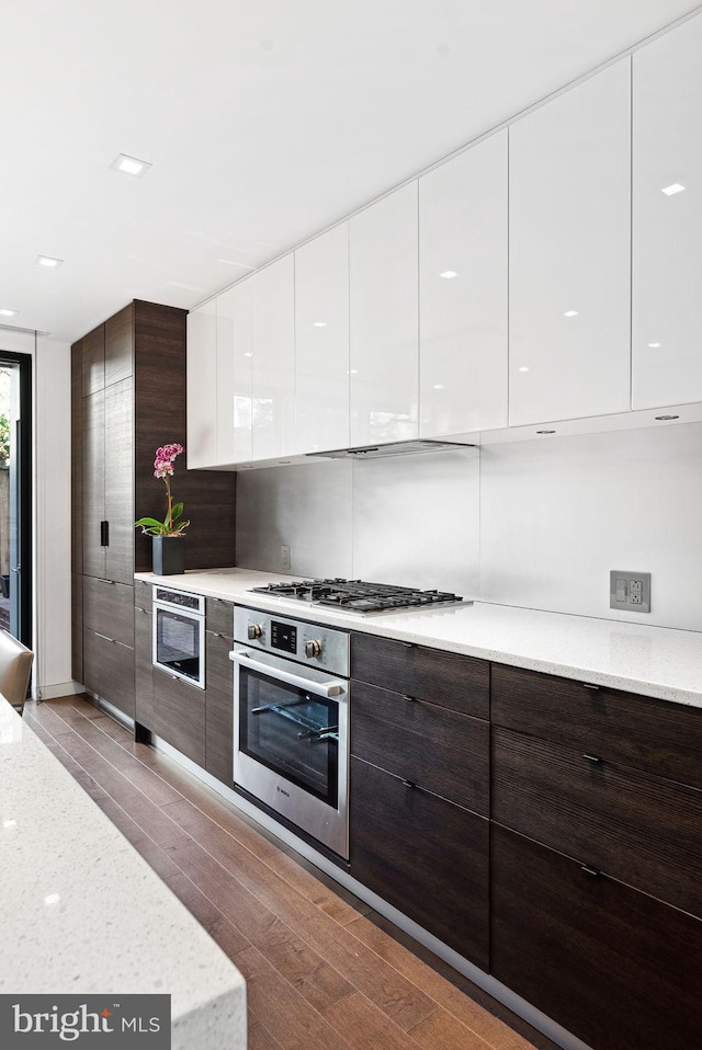 kitchen with dark brown cabinetry, white cabinetry, stainless steel appliances, and modern cabinets