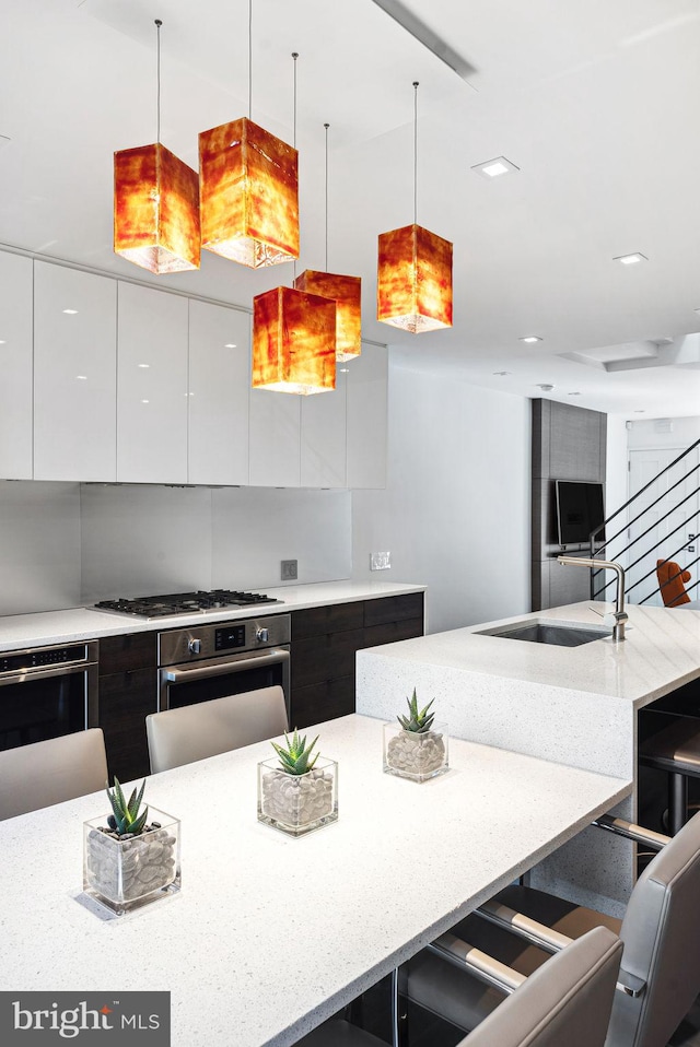 kitchen featuring a breakfast bar area, stainless steel appliances, white cabinets, modern cabinets, and a sink