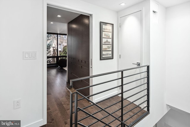 hallway with wood finished floors and an upstairs landing