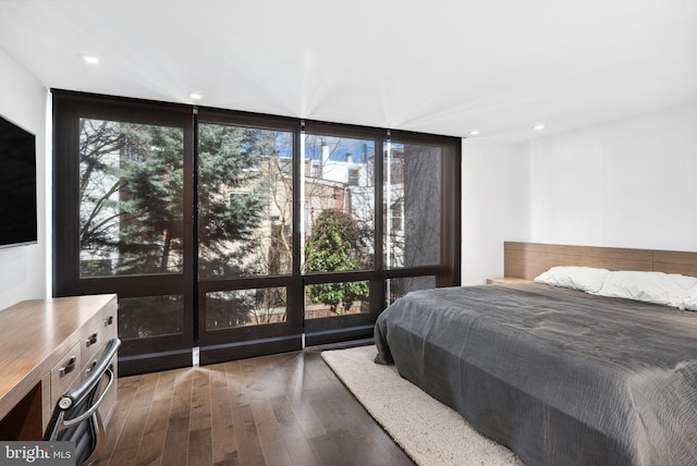 bedroom featuring a wall of windows, recessed lighting, and wood finished floors