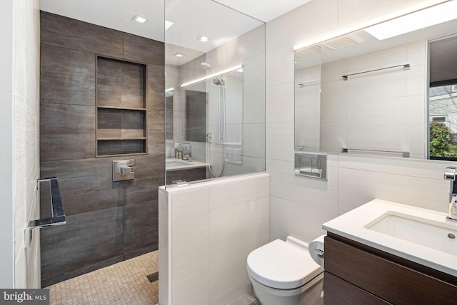 full bath featuring tiled shower, toilet, tile walls, and vanity