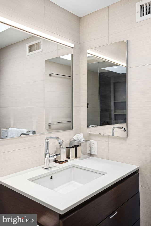 bathroom featuring vanity, tile walls, and visible vents