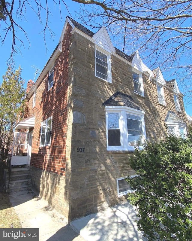 view of side of property featuring stone siding, brick siding, and a chimney