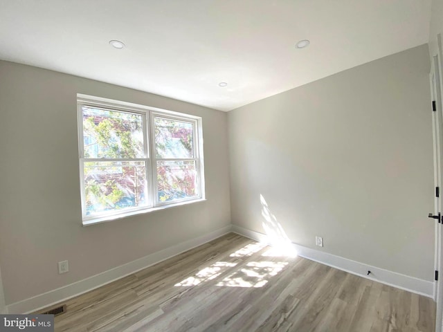 unfurnished room featuring visible vents, light wood-style floors, and baseboards