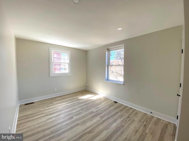 spare room featuring baseboards, plenty of natural light, visible vents, and light wood-style flooring