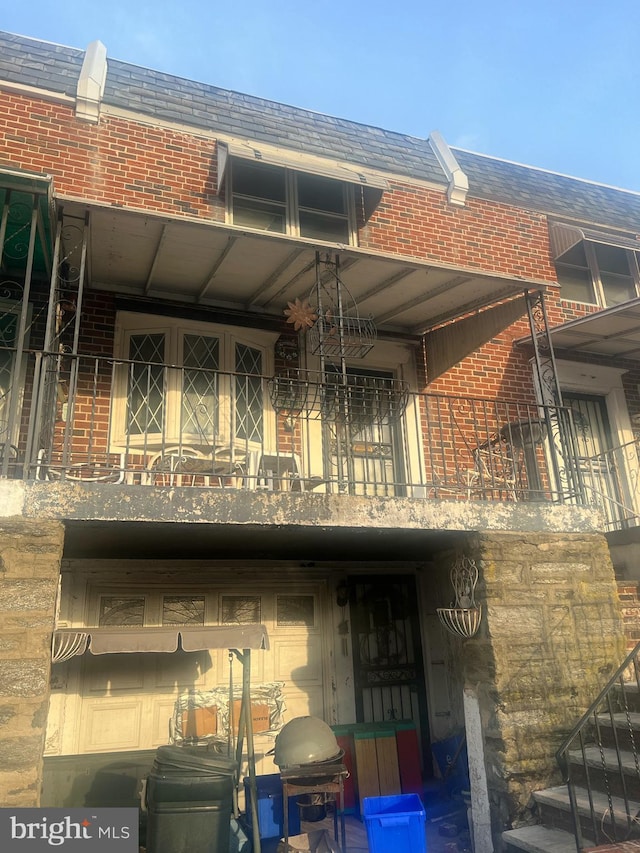 rear view of property featuring brick siding and a balcony