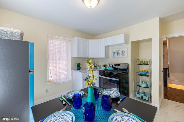 kitchen with baseboards, light countertops, stainless steel appliances, marble finish floor, and white cabinetry