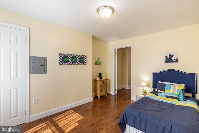 bedroom with electric panel, wood finished floors, and baseboards