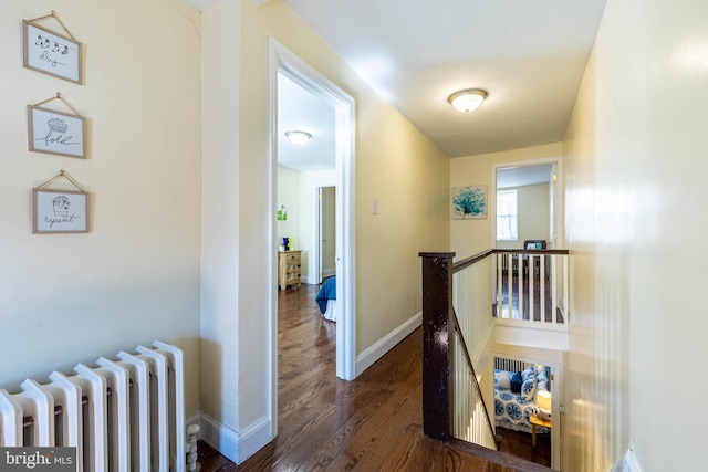 hall with baseboards, an upstairs landing, wood finished floors, and radiator heating unit